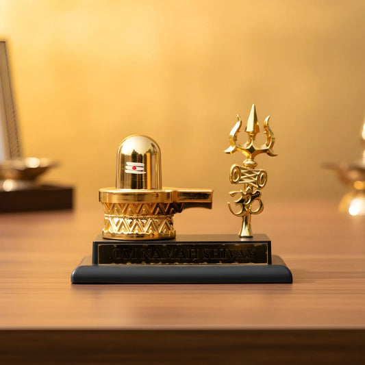 Gold Shiva Lingam and Trishul on a wooden surface with a warm background
