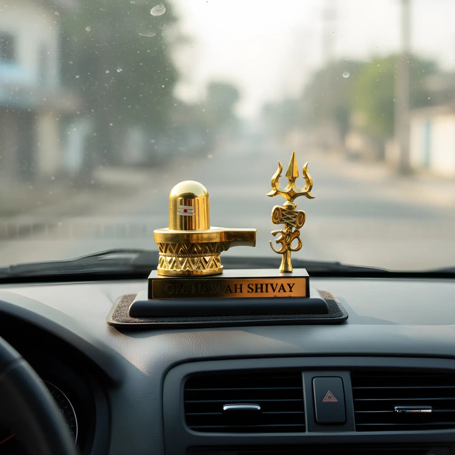 Decorative items on a car dashboard with a blurred street background