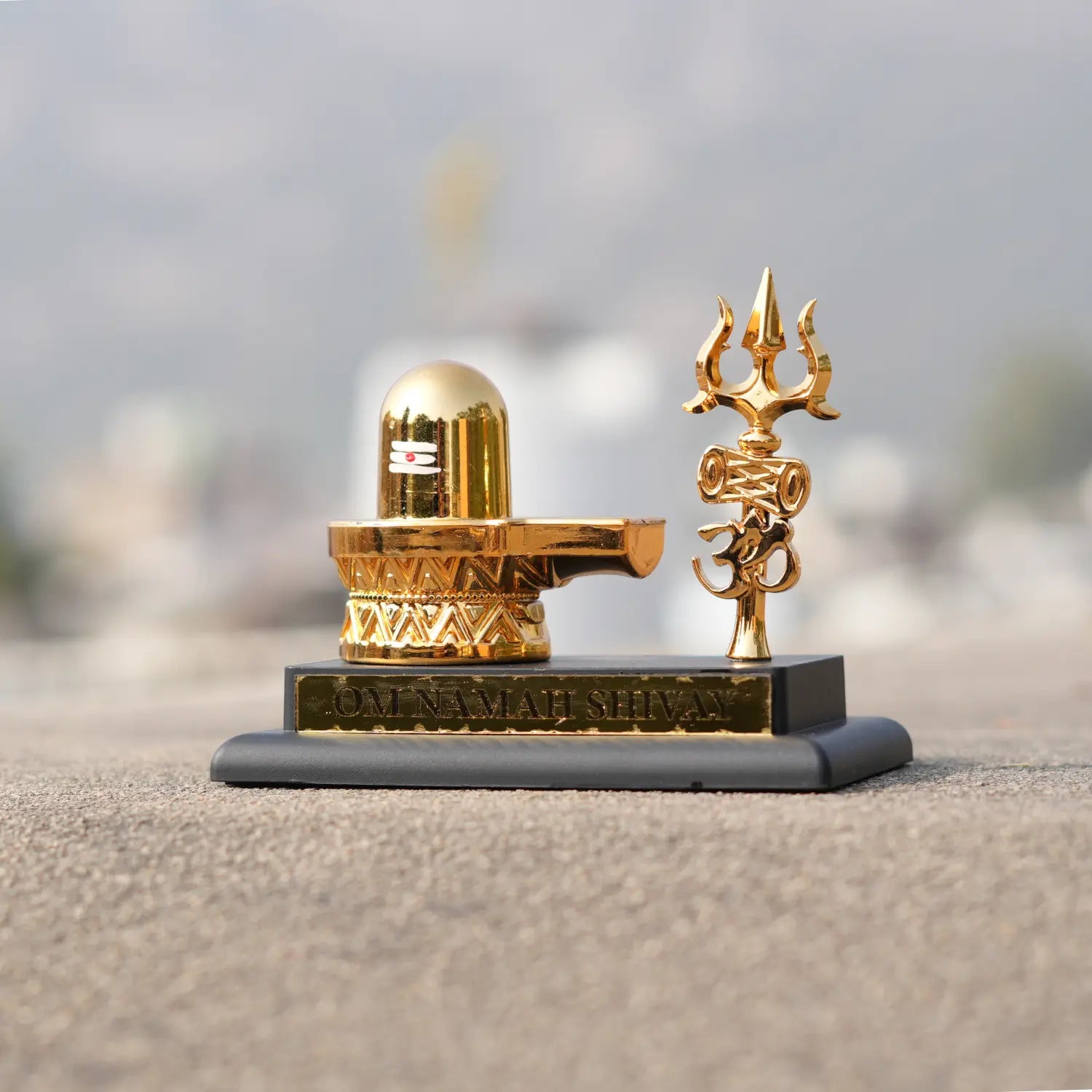 Gold Shiva Lingam and Trishul on a gray base with a blurred background