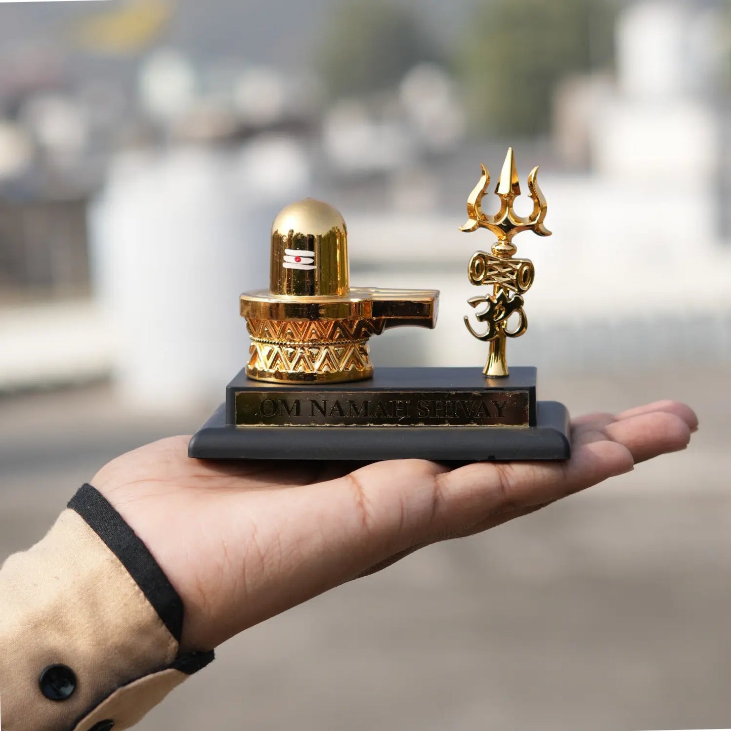 Hand holding a small golden statue with a blurred background