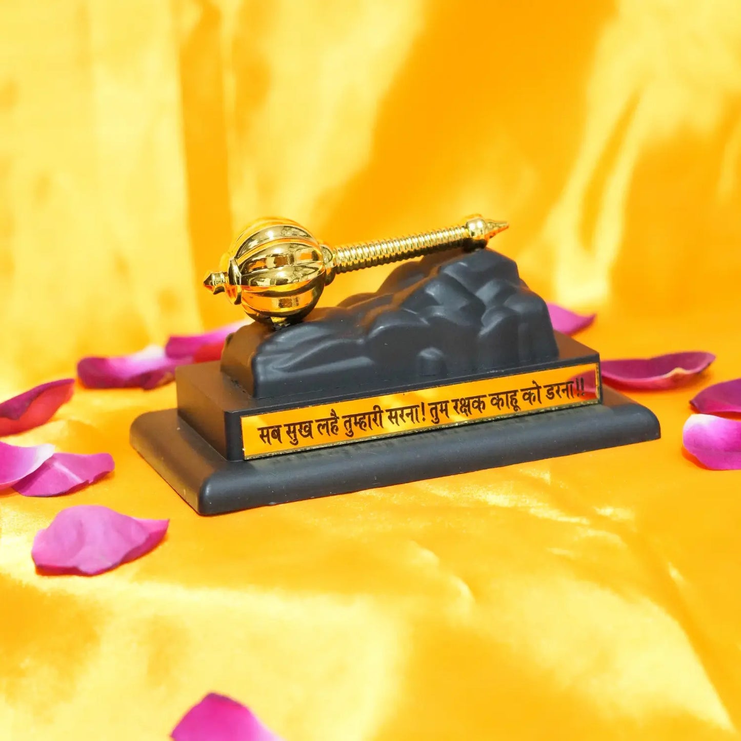 Decorative object with a golden螺旋桨 on a black base, surrounded by pink petals on a yellow background