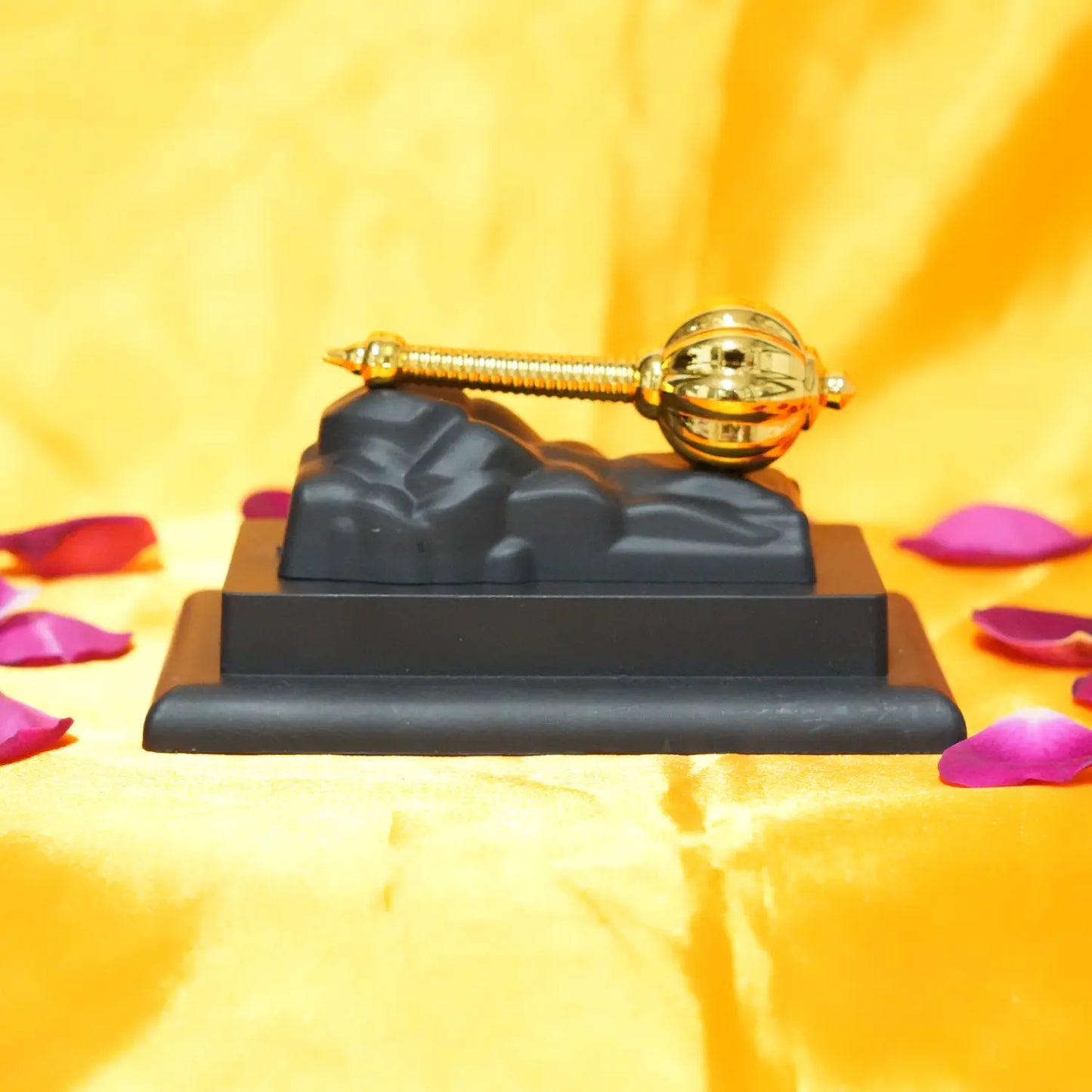 Decorative item with a gold螺旋and black base on a yellow background with pink petals.