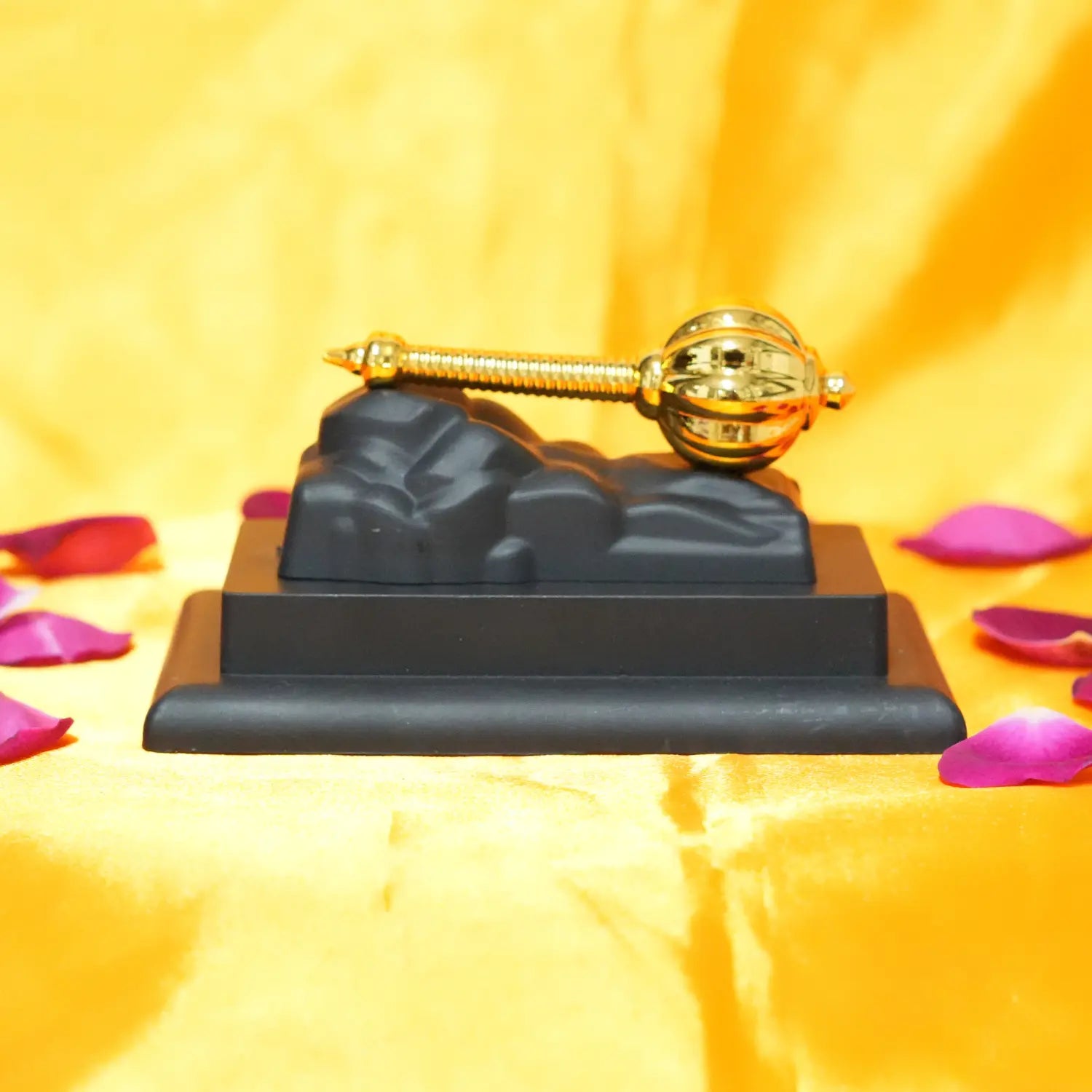 Decorative item with a gold螺旋and black base on a yellow background with pink petals.