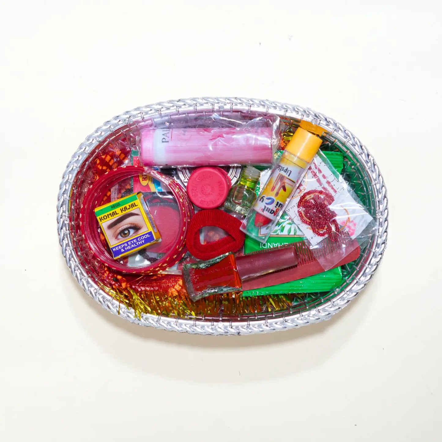 Assorted makeup and beauty products in a decorative tray on a white background