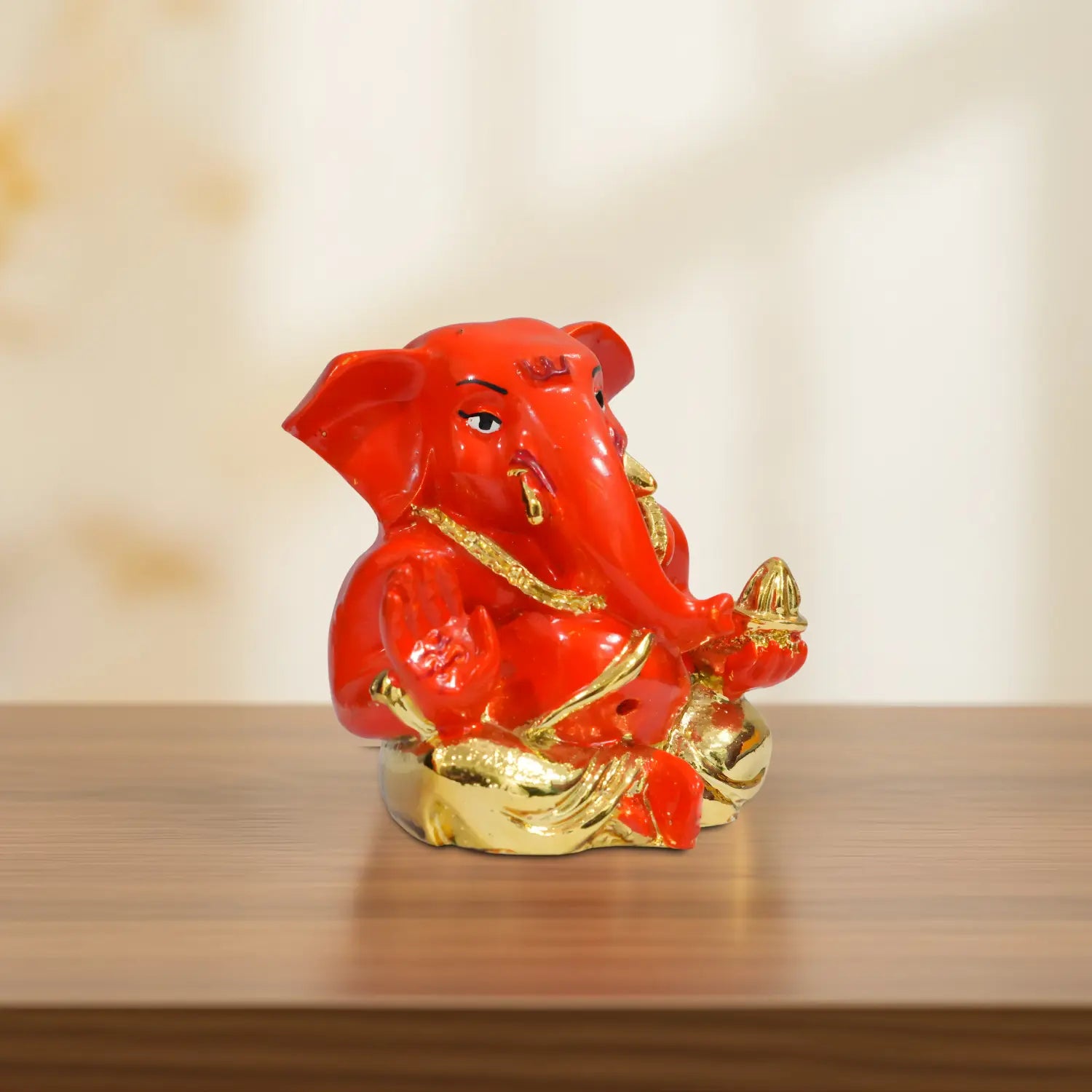 Red and gold elephant statue on a wooden surface with a blurred background