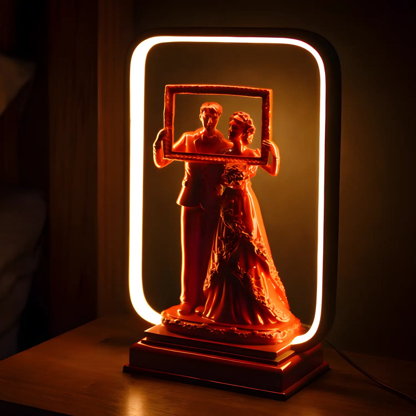 Decorative lamp with a couple holding a frame, illuminated by a warm light.