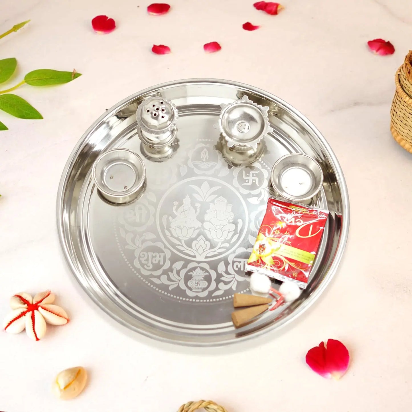 Decorative silver tray with religious symbols on a light background with red flower petals.