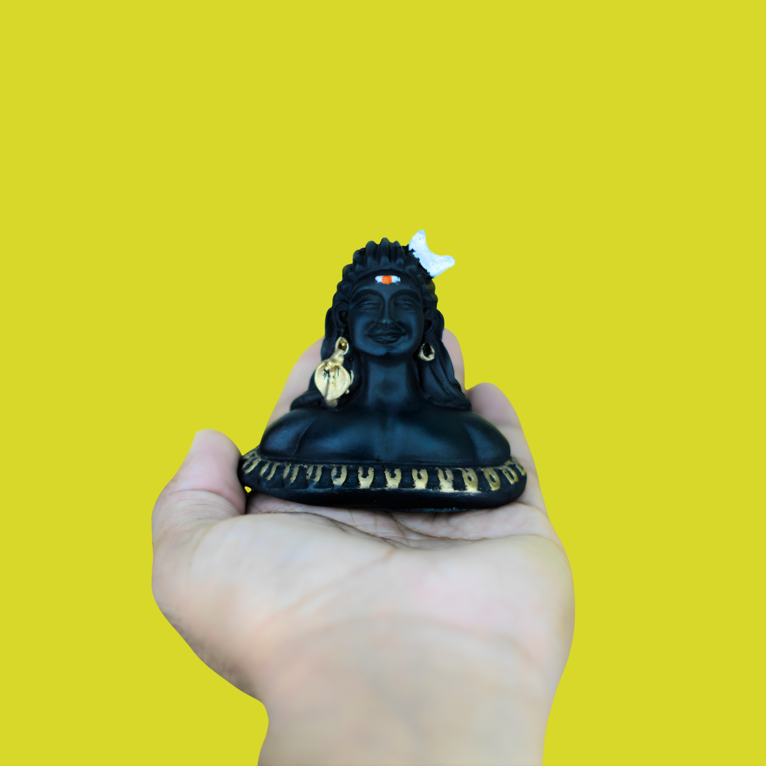 Black statue held in a hand against a yellow background