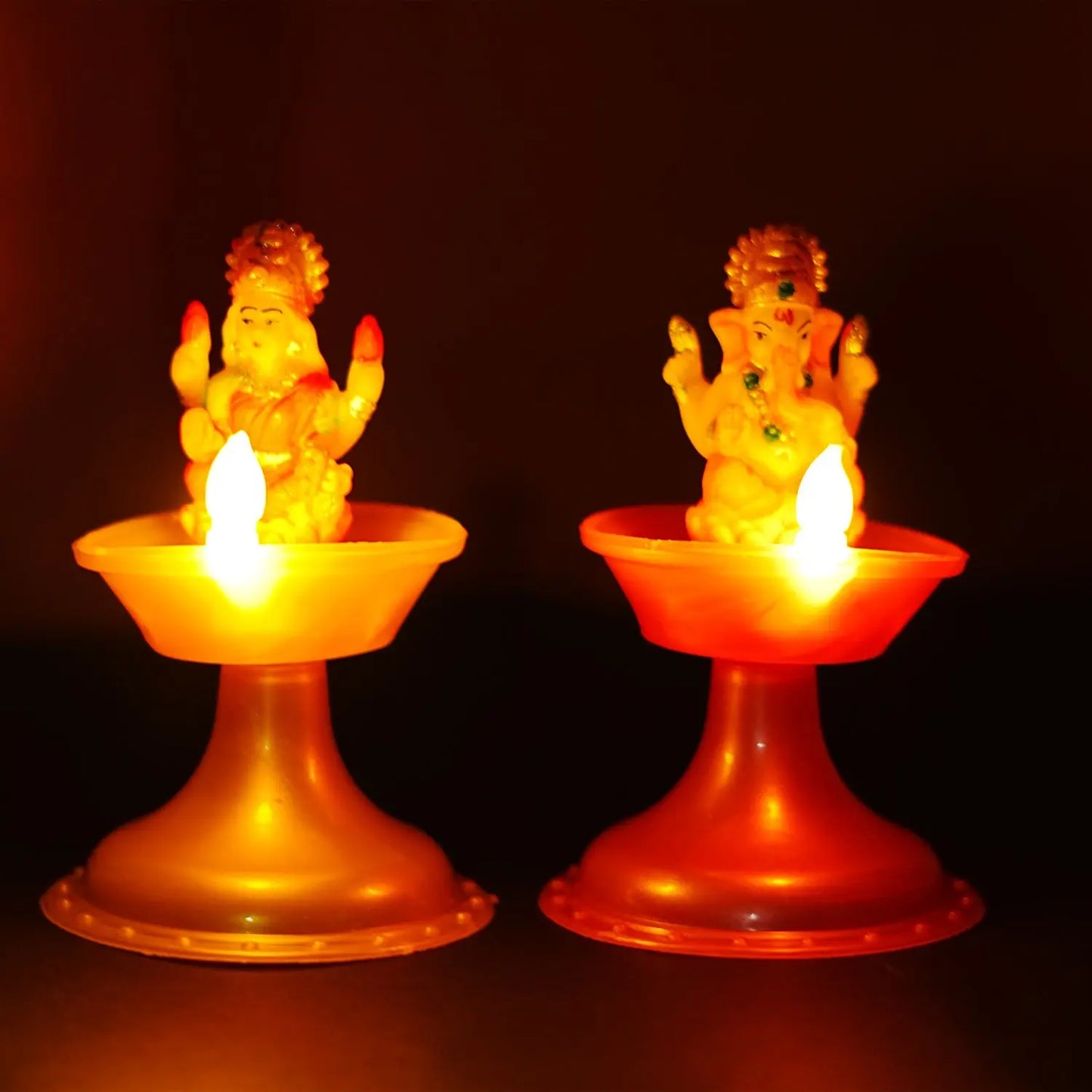 Two illuminated candle holders with figurines on a dark background, Water Sensor Laxmi ganesh Diya.