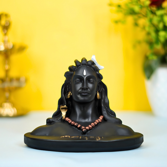 Black Shiva statue with jewelry on a white surface against a yellow background