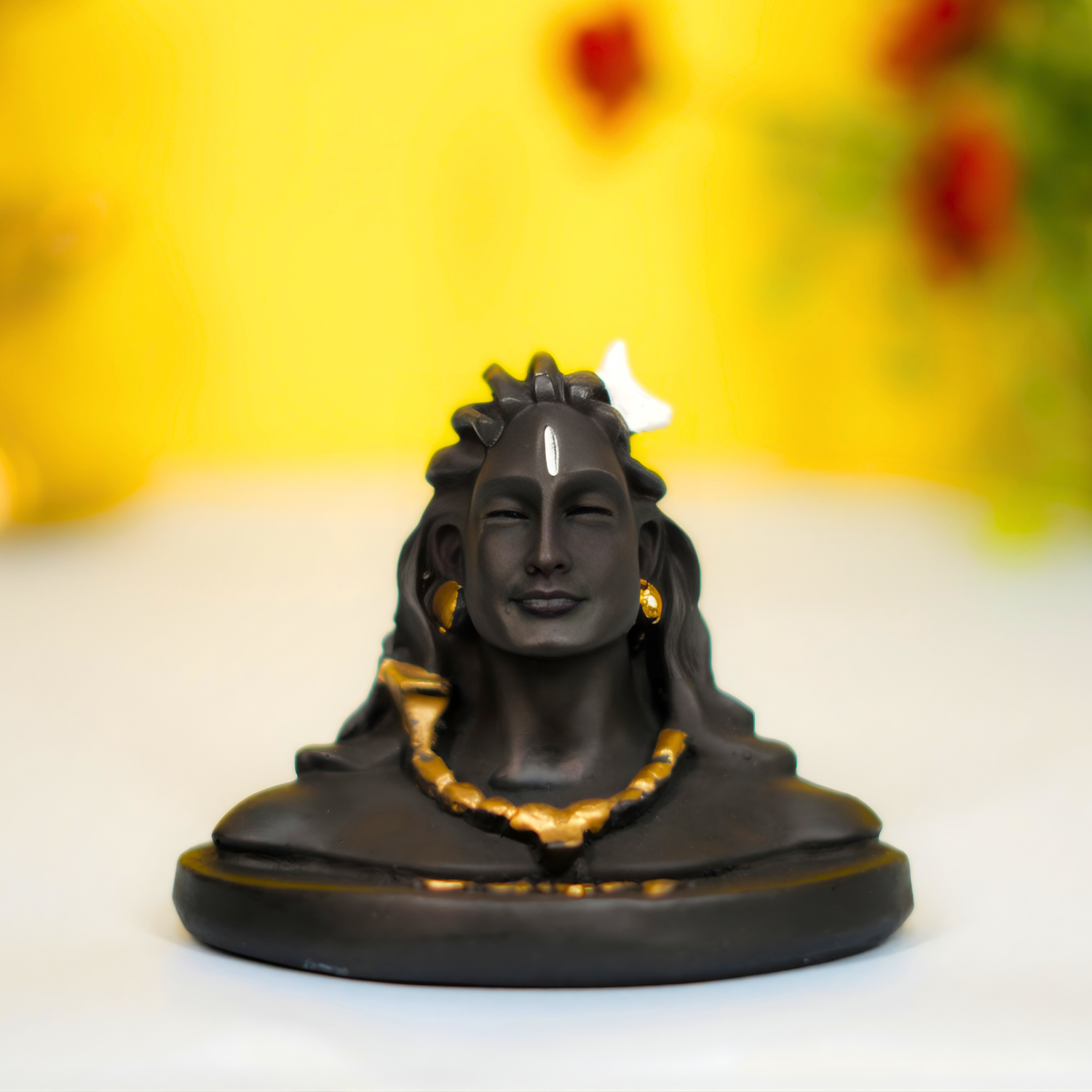 Black statue with gold accents on a white surface with a blurred yellow background