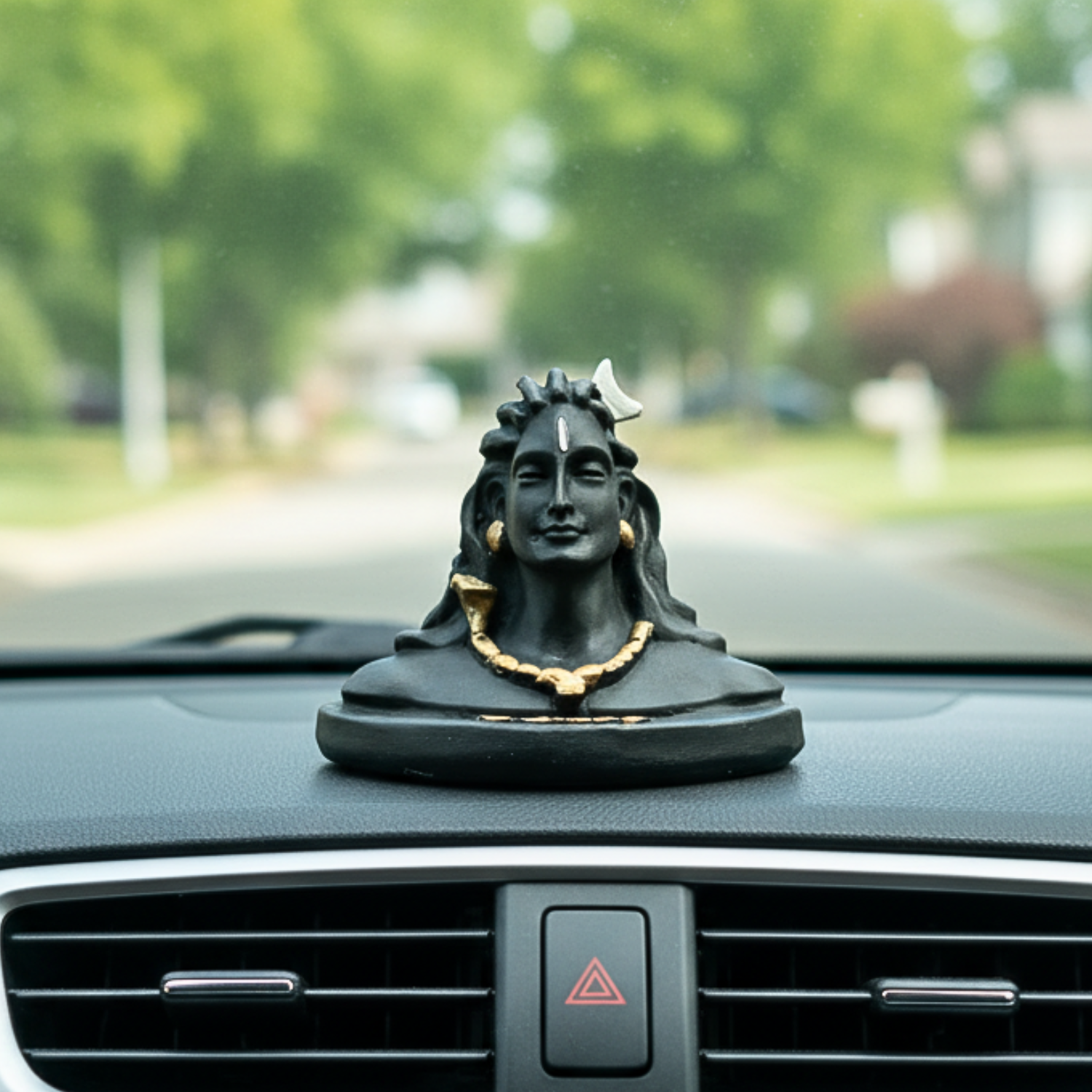 Decorative statue on a car dashboard with a blurred outdoor background
