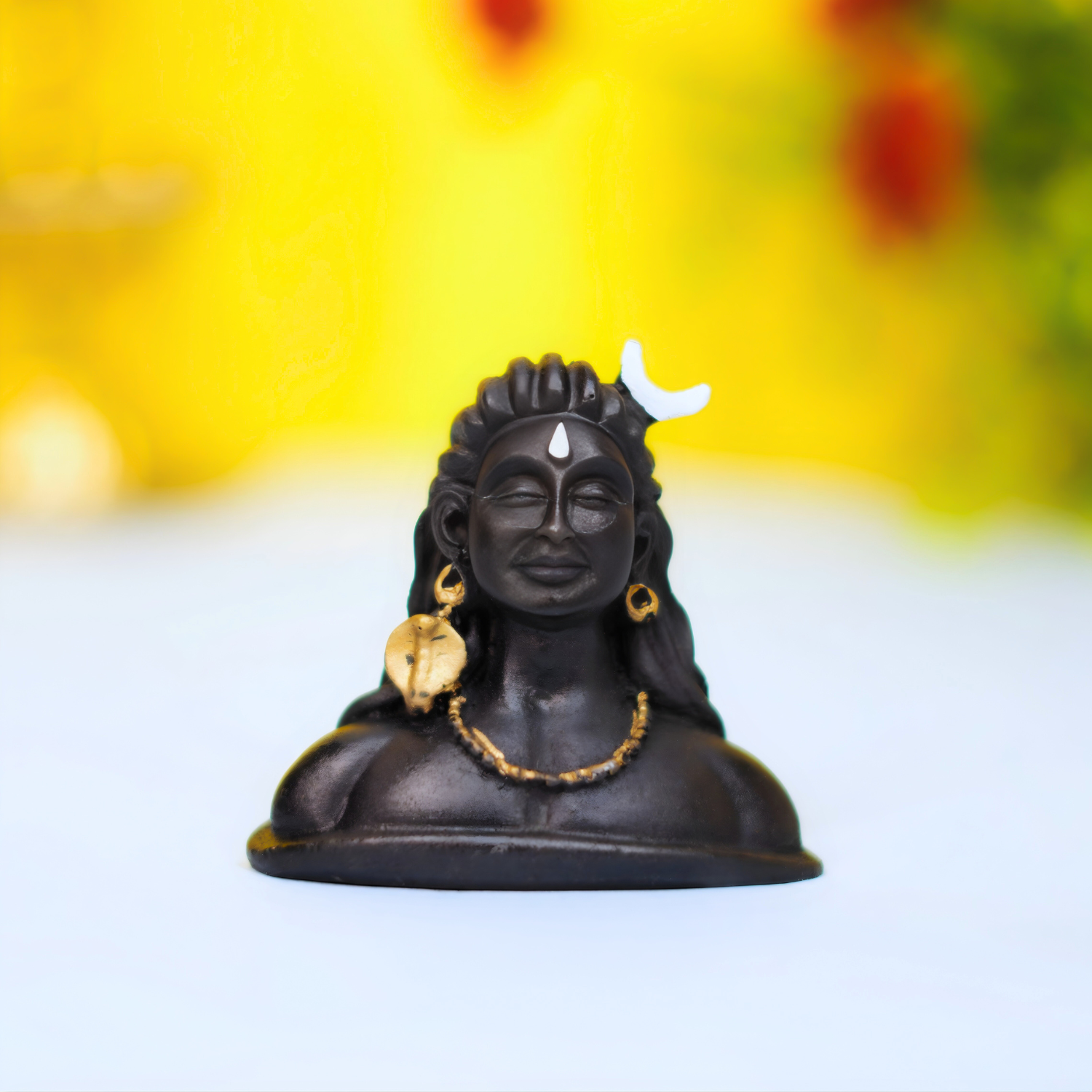 Black figurine with gold accents on a white surface with a blurred colorful background