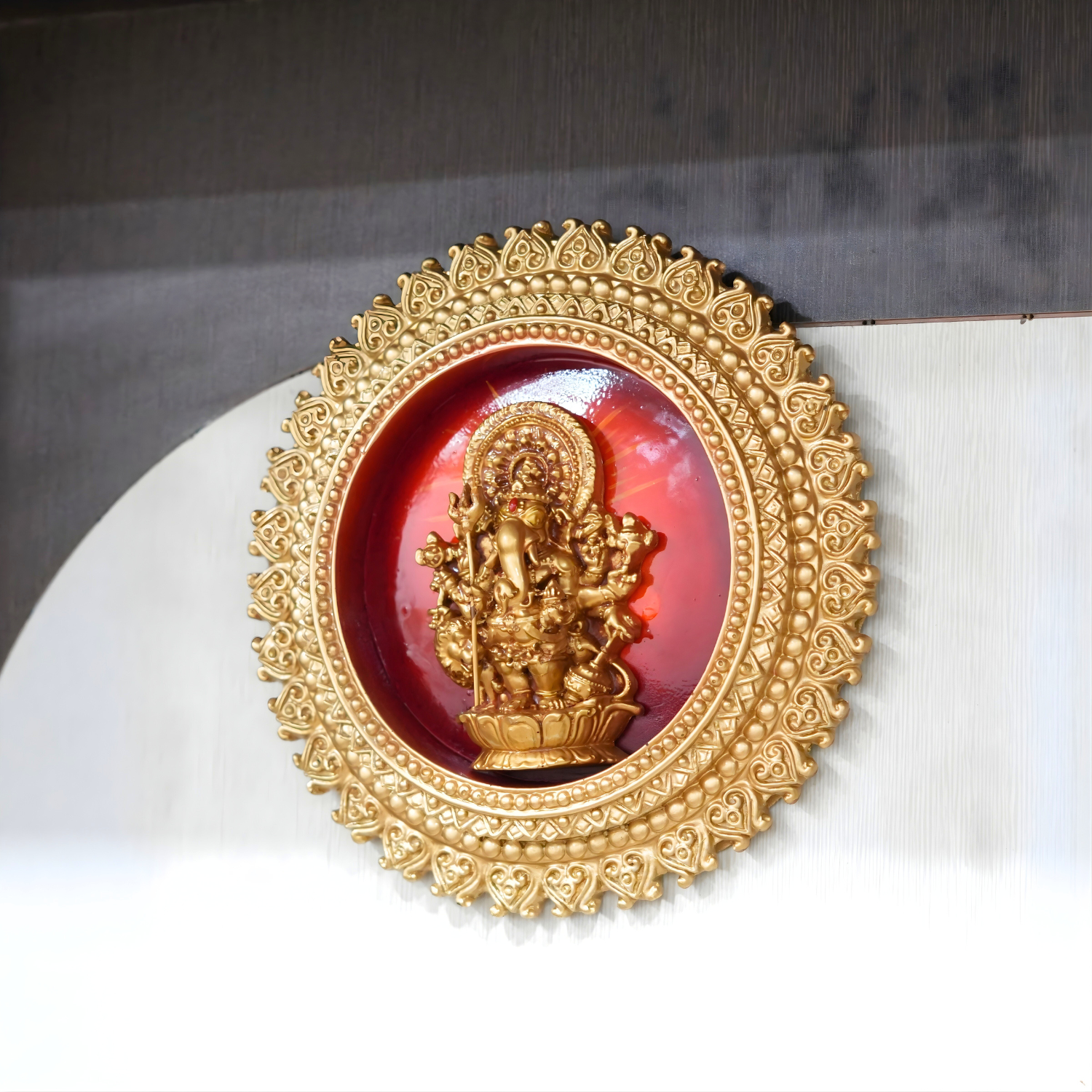 Decorative item with gold frame and red center featuring a figure, on a white surface.