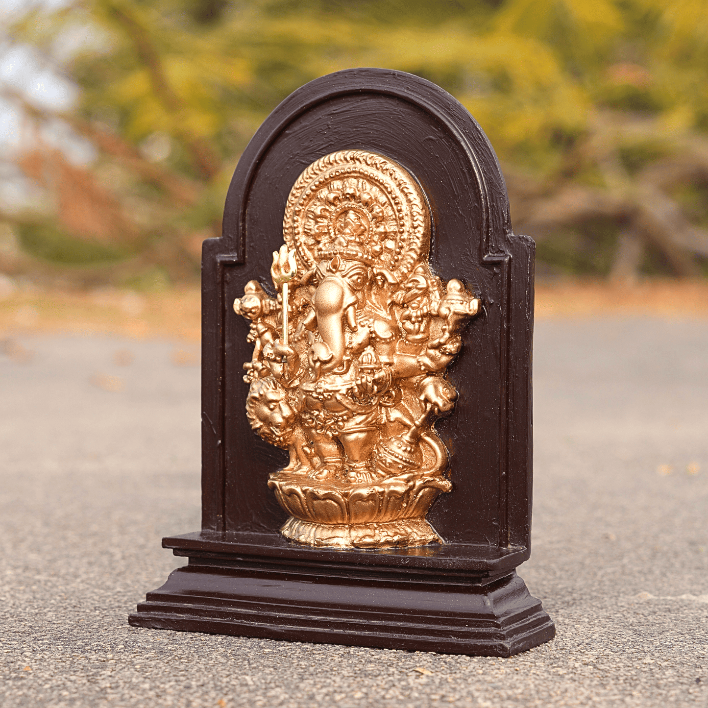 Decorative statue with gold and black finish on a blurred natural background