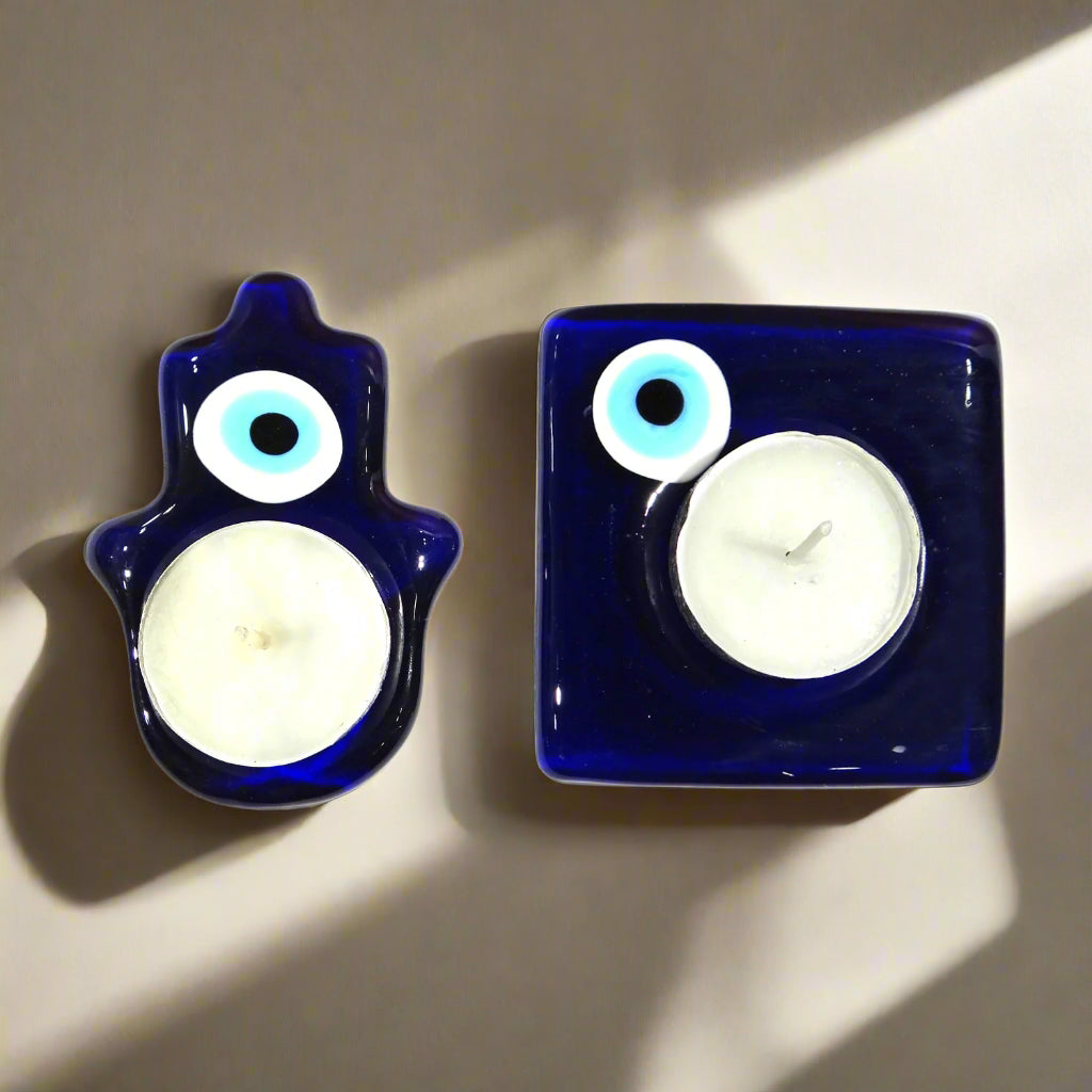 Two blue glass candle holders with white candles inside on a white background