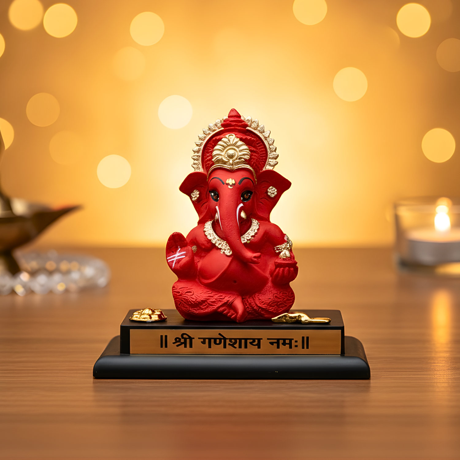 Red Ganesha statue on a wooden platform with a blurred golden background