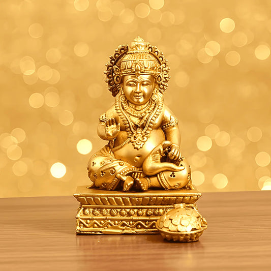Gold-colored statue of a seated figure on a wooden surface with a blurred golden background
