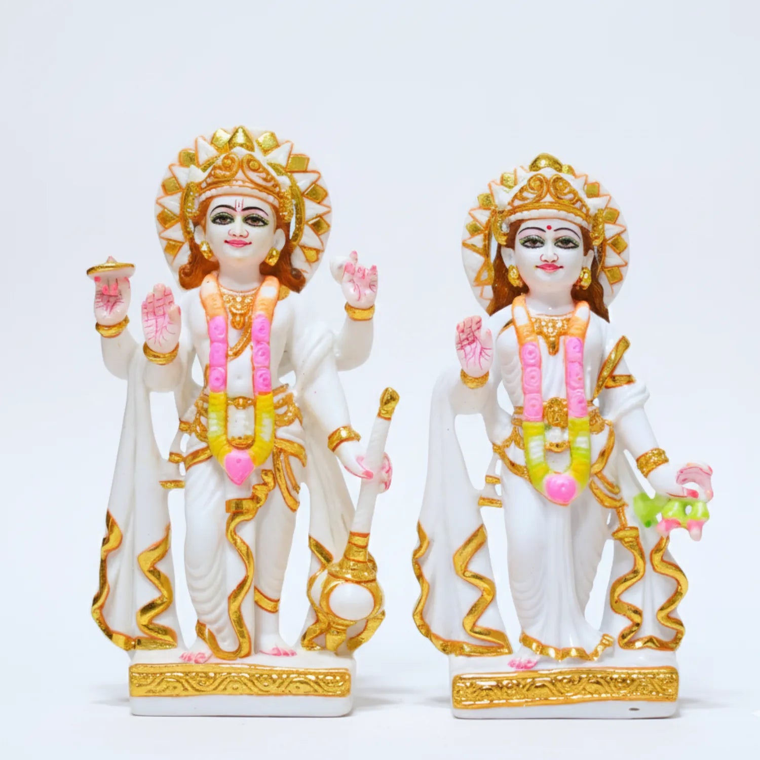 Two ornate statues with gold and pink accents on a white background