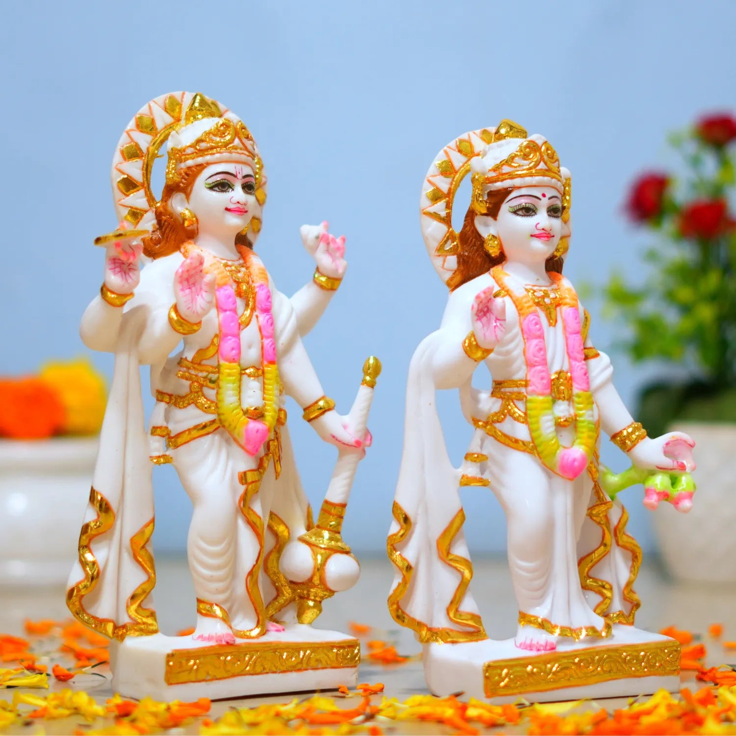 Two ornate statues with gold and pink details on a decorative surface.