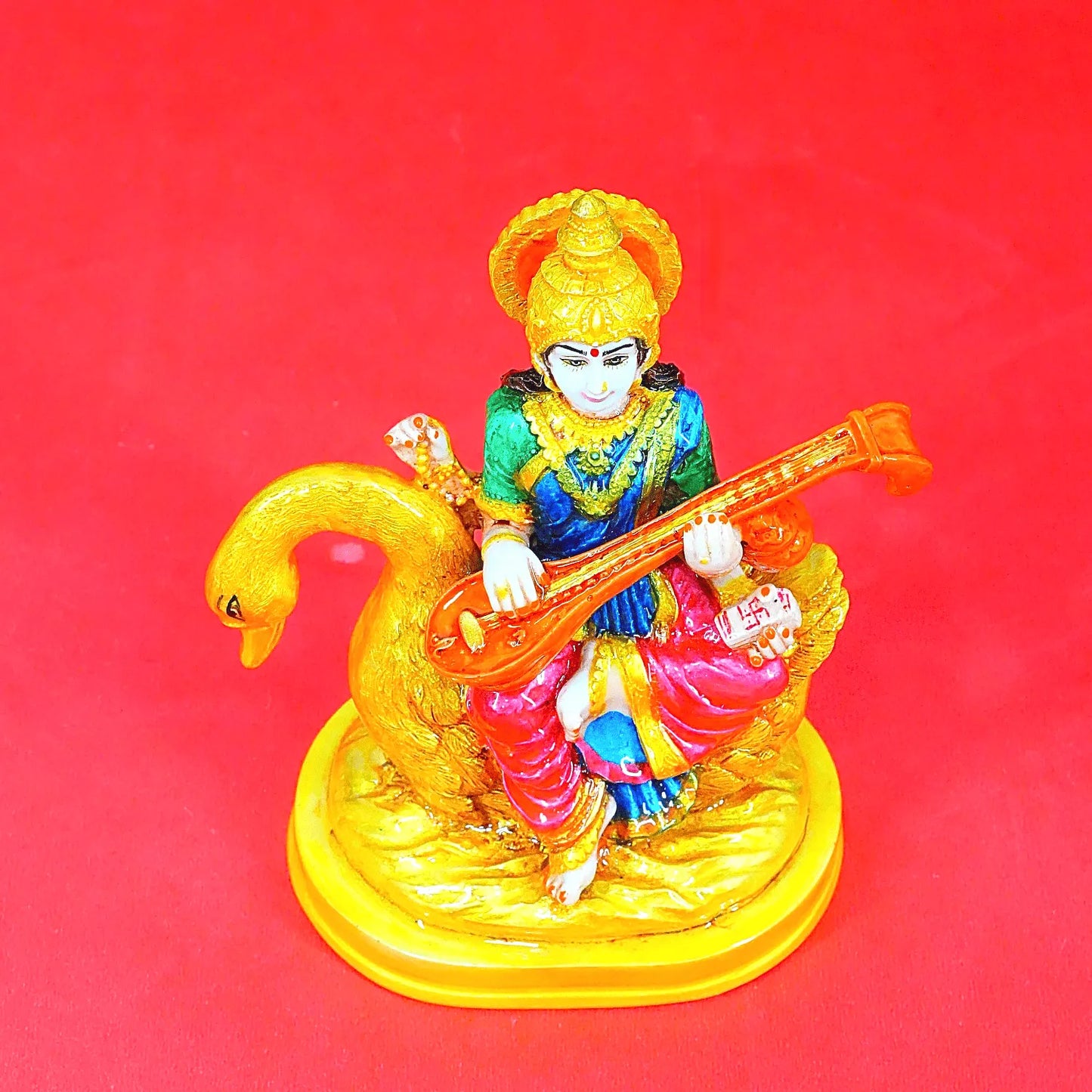 Colorful figurine of a deity playing a instrument on a red background