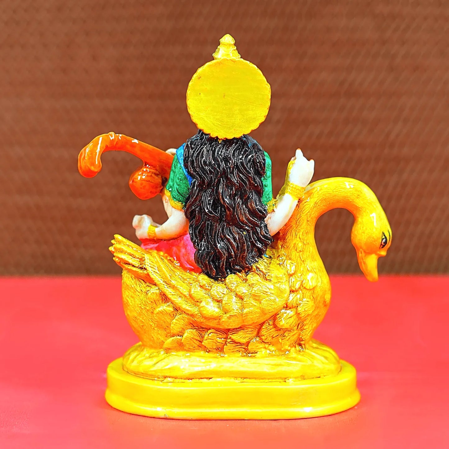 Colorful figurine of a deity on a swan with a yellow background