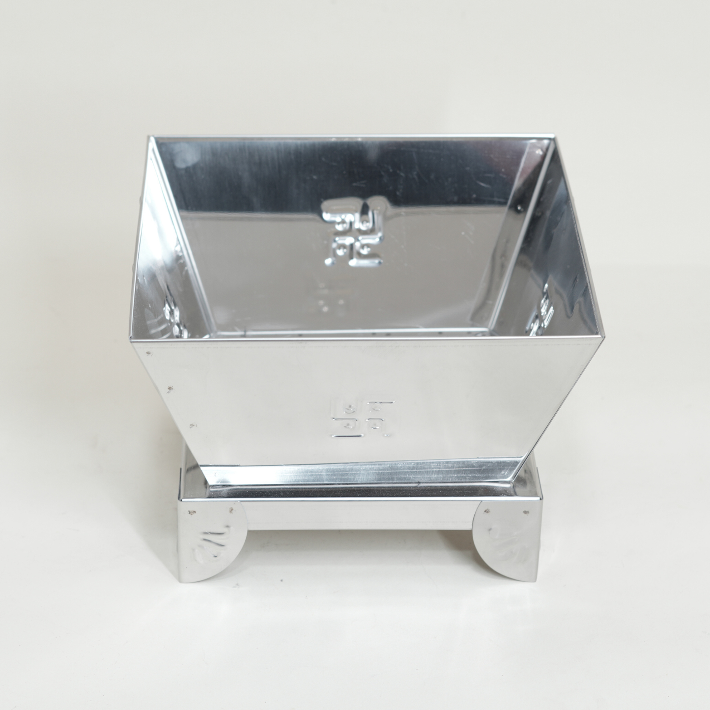 Metallic square container with reflective surface on a white background