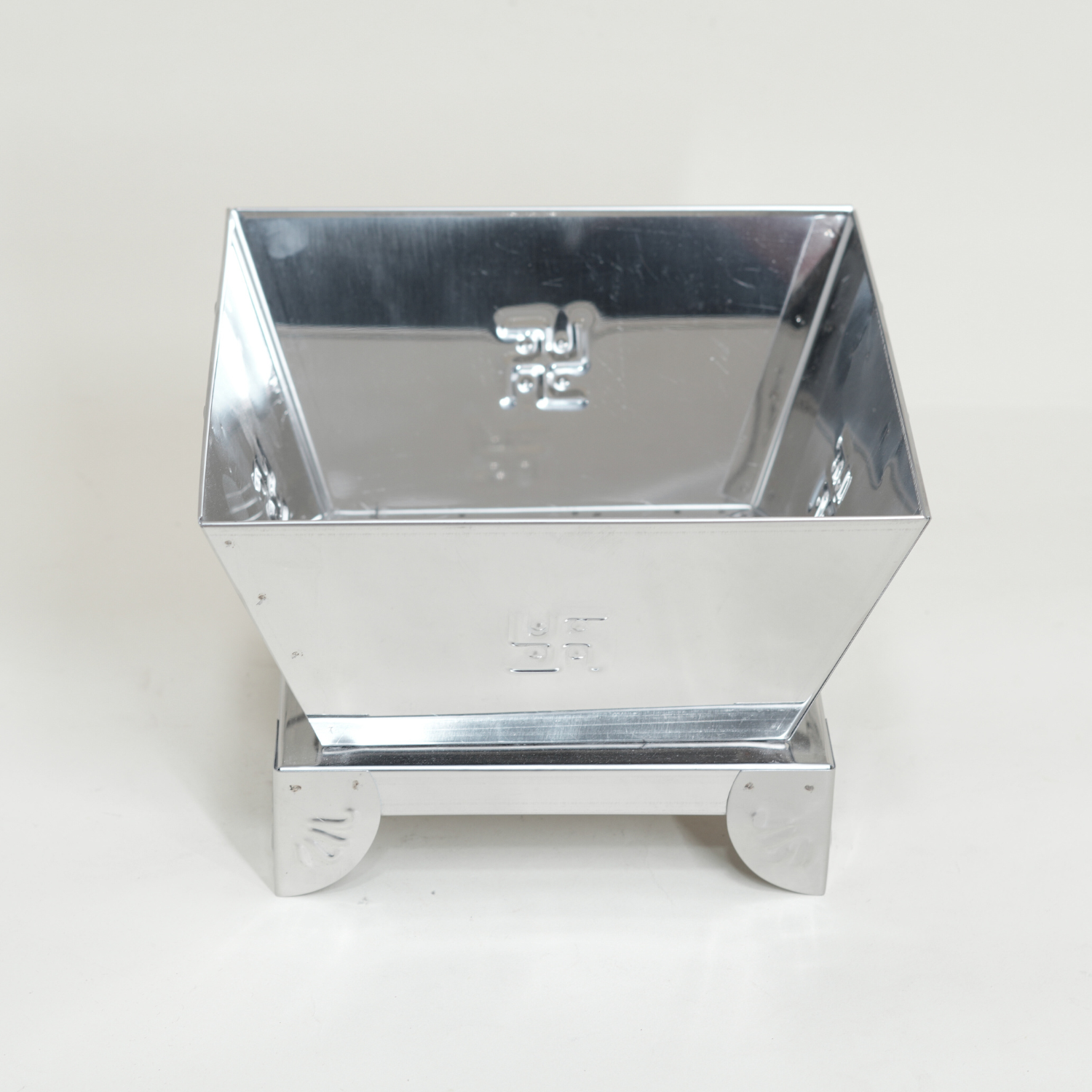Metallic square container with reflective surface on a white background