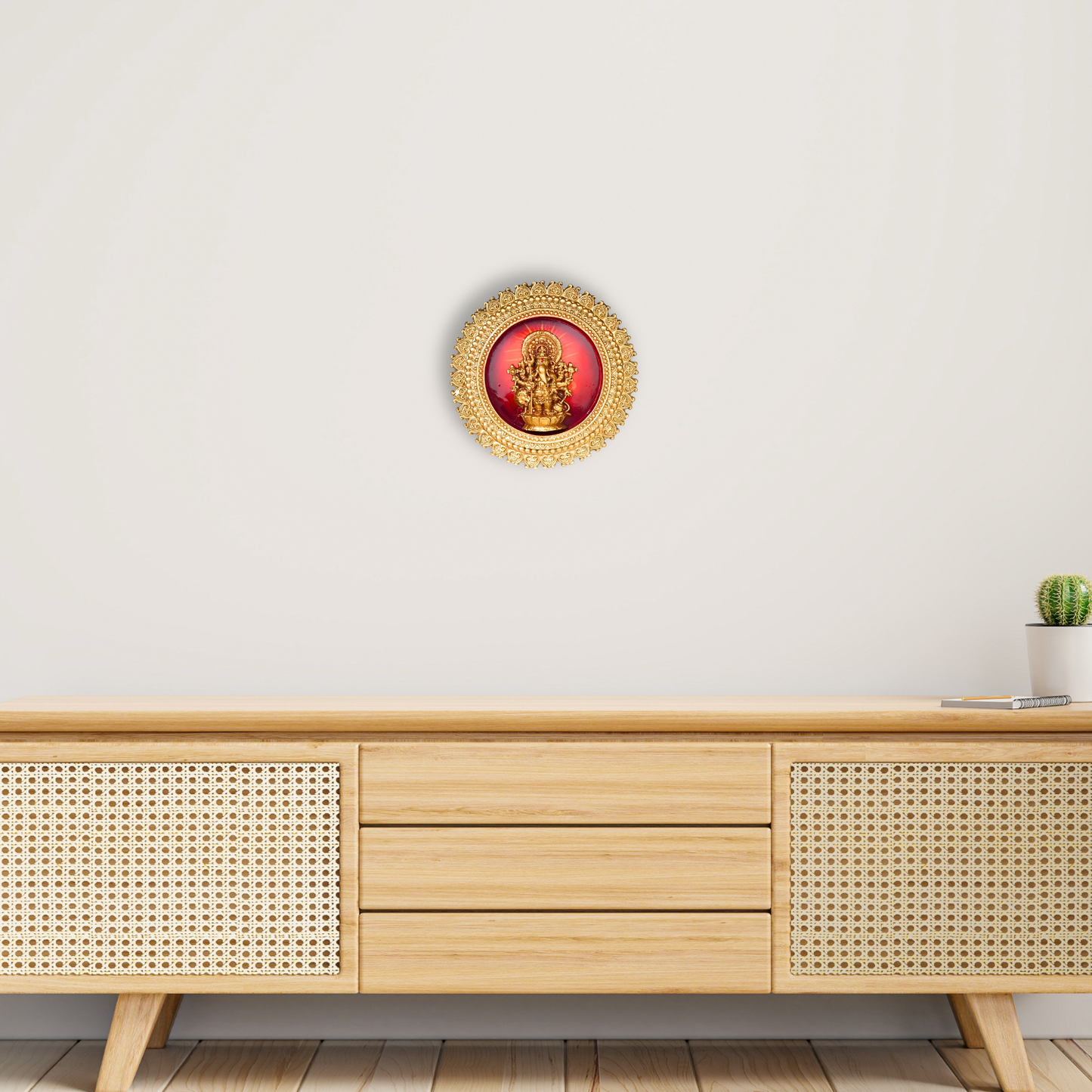 Decorative wall art with a red center and gold frame on a white wall above a wooden cabinet.